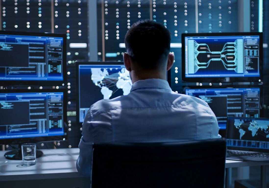 A man sitting in front of multiple computer screens.