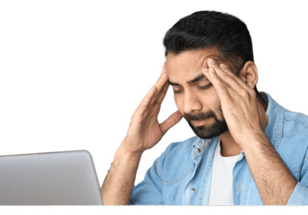 A man sitting at a table with his hands on his head.